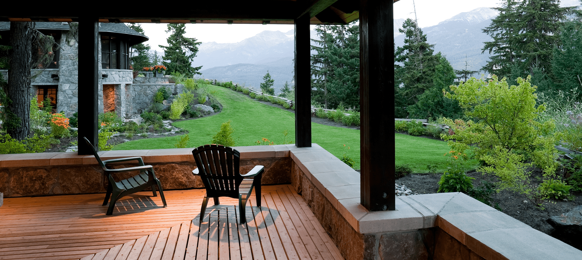 A wooden chair on a porch overlooking a green garden and mountains.